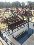 Кованная скамейка на кладбище с деревянным сиденьем